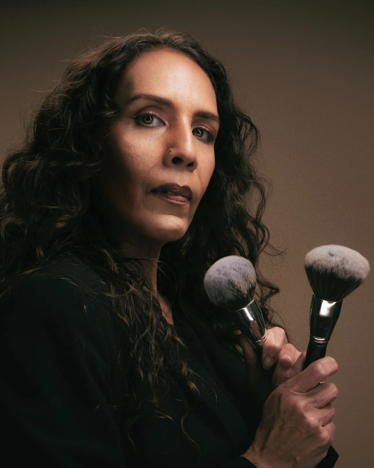 Portrait artist holding makeup brushes in a Mount Up Media studio